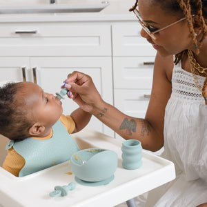 Mom feeds baby boy in high chair with BooginHead Baby Led Weaning Kit