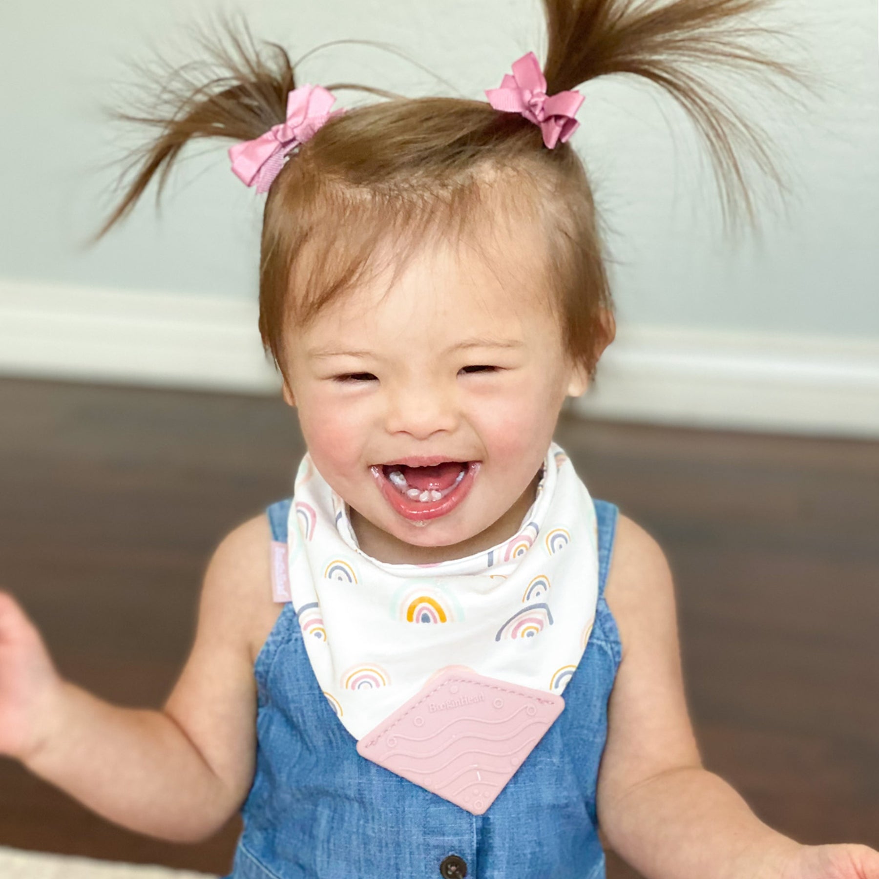 Happy baby girl wears BooginHead Bandana Teether Bib Pink Rainbows