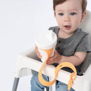 Toddler using BooginHead SippiGrip sippy cup strap in Creamsicle Orange. Hold sippy cups, bottles and toys to high chairs and strollers