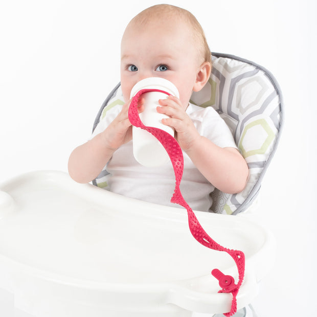 Baby using BooginHead SippiGrip Silicone sippy cup strap in Hot Pink . Hold sippy cups, bottles and toys to high chairs and strollers