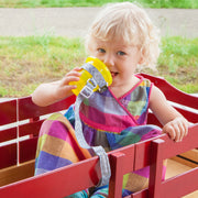 Toddler using BooginHead SippiGrip in Go Go Chevron to keep the sippy cup clean and attached to their wagon. Size adjustable strap can attach to bottles, sippy cups or toys. Essential baby and toddler supply! Easy to clean. 