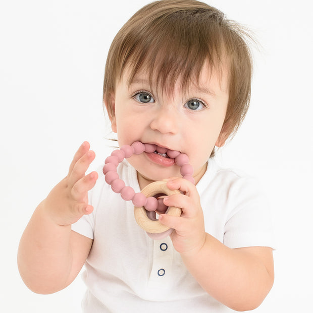 Baby using BooginHead silicone & wood teether, pink heart